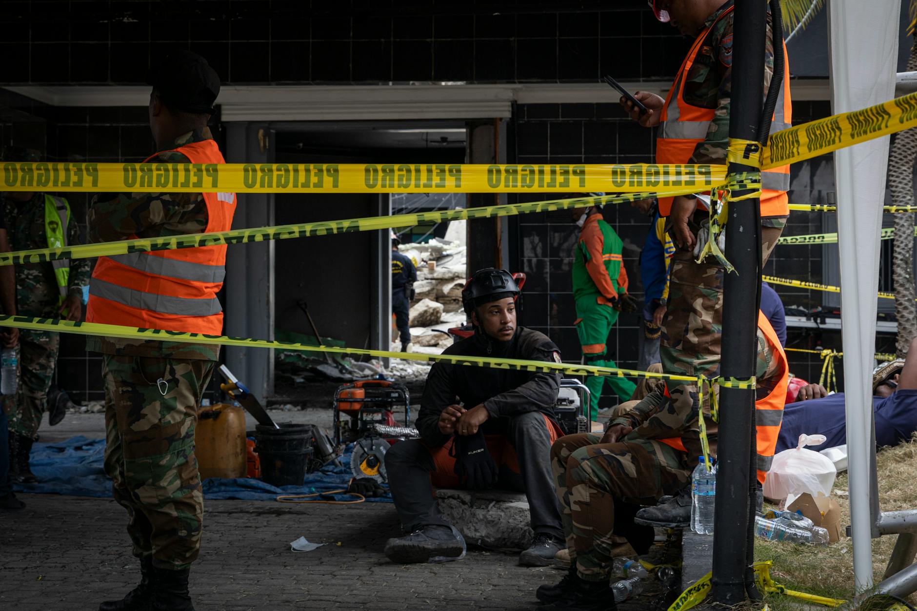 Ratownicy w kaskach pracują na odgrodzonym taśmą terenie budowy