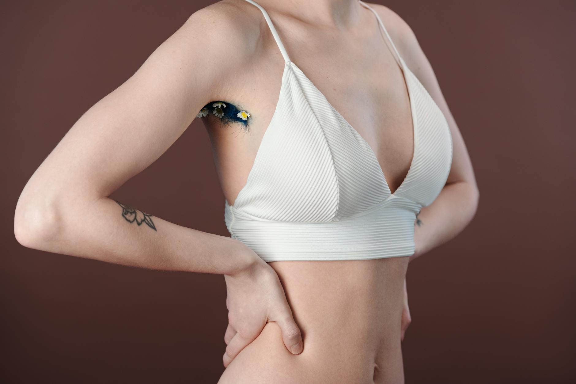 Ciało obce w ranie: kiedy zostawić, jak ustabilizować i co przekazać ratownikom Zbliżenie kobiecej pachy z kwiatowym tatuażem w białym topie