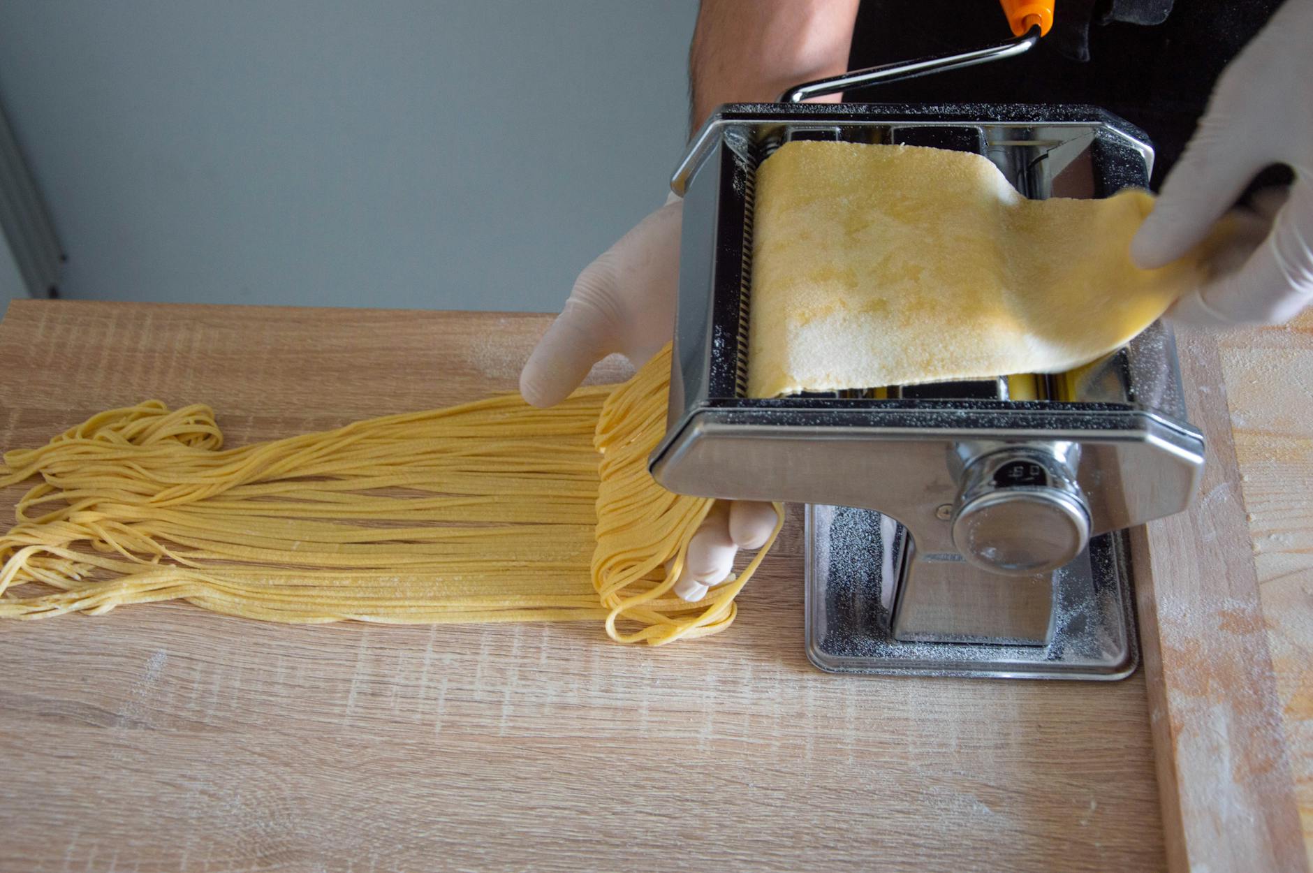 Maszynka do makaronu wycina świeże spaghetti w domowej kuchni